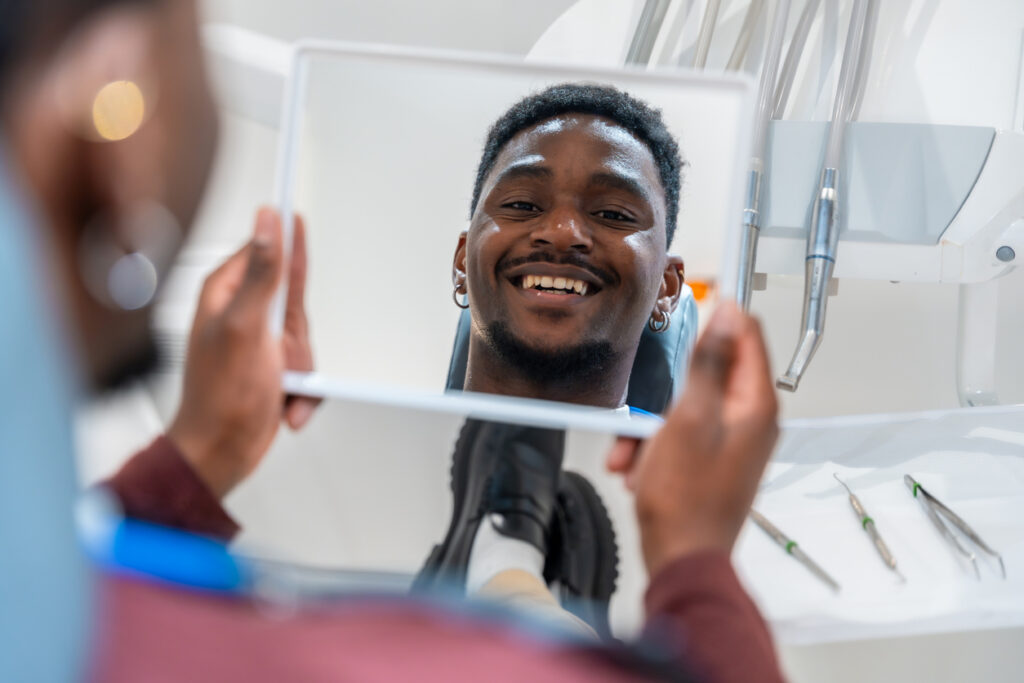 Young man sitting in the dental chair with a mirror