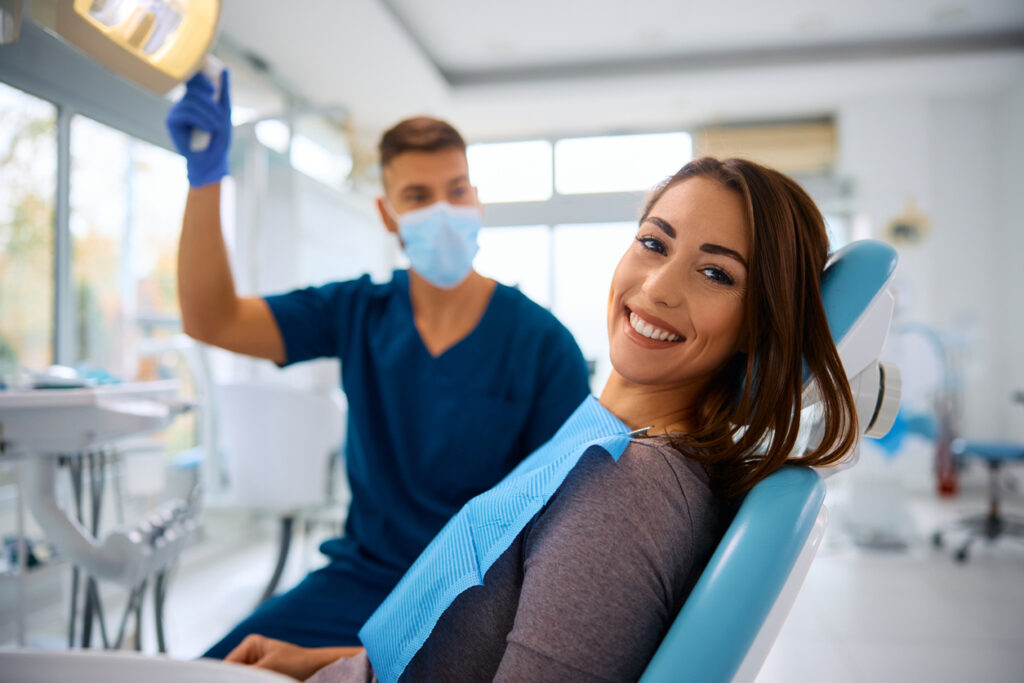 Dental patient smiling in the dental chair with the dentist in the background