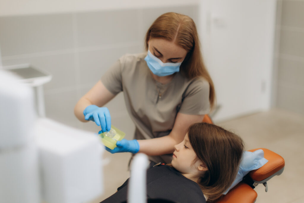 dental hygienist giving a pediatric patient fluoride